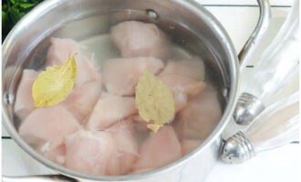 Retirez les membranes du filet de poulet et coupez-le en morceaux assez gros. Mettez la viande dans une casserole, ajoutez-y une feuille de laurier et couvrez d'eau froide. Placez le récipient sur le feu et portez l'eau à ébullition en récupérant la mousse qui s'est formée à la surface. Laisser mijoter le bouillon pendant 15 minutes, puis retirer la viande dans une assiette.