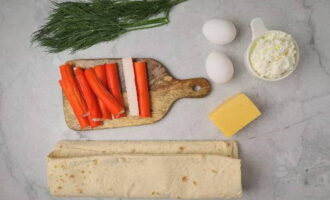 Ang lavash roll na may crab sticks ay napakadaling ihanda. Ihanda ang mga sangkap. Pakuluan nang husto ang mga itlog. Pagkatapos ng paglamig at pagbabalat, lagyan ng rehas ng magaspang. Ginagawa namin ang keso sa malalaking shavings sa parehong paraan.