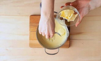 Die Schüssel mit der Sahne vom Herd nehmen. Butter portionsweise dazugeben und nach jeder Portion alles gut vermischen.