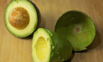 Lavare l'avocado, tagliarlo a metà ed eliminare la buccia e il nocciolo.