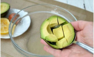 Ang hinog kong avocado. Hinahati ang pahaba, inilabas namin ang buto. Gupitin ang pulp sa mga cube at ilabas ito gamit ang isang kutsara. Ilipat sa isang mangkok.