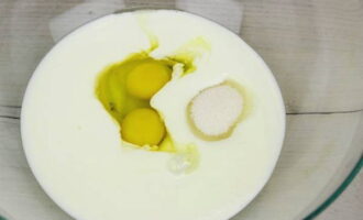 Ora potete preparare l'impasto per le crostate. Versa il kefir caldo in una ciotola, puoi prenderlo con qualsiasi contenuto di grassi. Rompere le uova di gallina nel kefir, aggiungere sale e zucchero e versare l'olio vegetale. Mescolare bene il tutto con una forchetta.