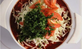 Tenslotte vullen we de samenstelling aan met fijngesneden kool, tomaten en kruiden met knoflook. Roer en zet na 10 minuten het vuur uit en laat afgedekt 30-40 minuten staan.