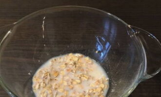 Geben Sie das Müsli in eine tiefe Schüssel und fügen Sie warme Milch hinzu. 20 Minuten einwirken lassen.