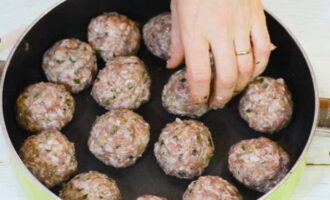 Molhamos as palmas das mãos em água e formamos bolinhas de tamanho médio, colocamos em uma frigideira funda, a uma curta distância umas das outras.