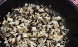 Selepas ini, masukkan champignons ke dalam bawang goreng. Teruskan memasak selama 5 minit lagi.