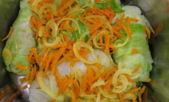 Coloca los rollitos de col en una cacerola grande, alternándolos con verduras fritas. Llénelo completamente con agua, agregue los granos de pimienta, la pasta de tomate y la crema agria. Llevar a ebullición y luego cocinar a fuego lento, tapado, durante unos 40 minutos.