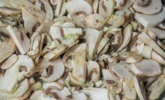 Gupitin ang mga champignon sa manipis na hiwa, i-chop ang sibuyas at bawang. Iprito ang mga produkto sa isang third ng mantikilya para sa mga 10 minuto.