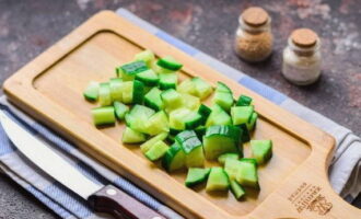 Ibuhos namin ang malamig na tubig sa sariwang pipino, alisin ang anumang mga dumi, kung mayroon man, at gupitin ang sangkap sa maliliit na cubes.