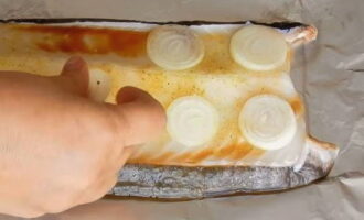 Peel the onions and cut into thin slices. Place these circles on the fish.