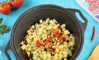 Após 5 minutos, adicione as batatas descascadas picadas e o alho, os anéis de pimenta sem sementes e os temperos.