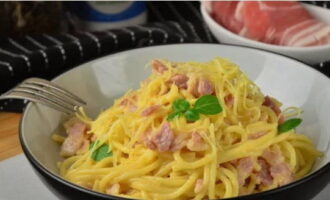 Klassisk carbonarapasta med bacon och grädde hemma är klar! Vi serverar rätten och tar genast ett prov. Smaklig måltid!