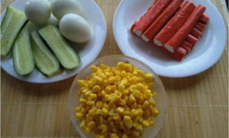 How to prepare a salad with crab sticks, corn, egg and cucumber according to the classic recipe? Boil and peel chicken eggs, drain the brine from the corn, and rinse the cucumbers.