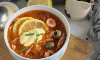 Ang klasikong mixed meat hodgepodge na may sausage ay handa na! Sa bawat plato, maglagay ng isang kutsara ng kulay-gatas, isa o dalawang hiwa ng lemon at ibuhos sa mainit na hodgepodge. Budburan ang ulam ng tinadtad na damo at ihain. Bon appetit!