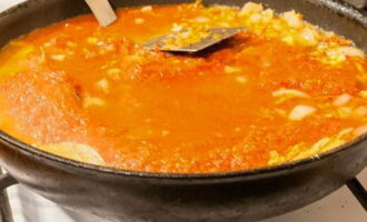 Aboqueu la salsa de tomàquet sobre el contingut de la paella. Remeneu i escalfeu bé.