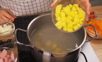 Stellen Sie die Pfanne auf den Herd. Geben Sie die Kartoffelscheiben in die abgesiebte, gekochte Brühe. Wir warten, bis es wieder kocht und kochen die Kartoffeln 20 Minuten lang.