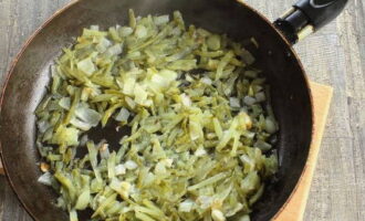 Rale pepinos em conserva pequenos e densos em um ralador grosso e adicione às cebolas salteadas. Frite tudo junto coberto por 5 minutos.