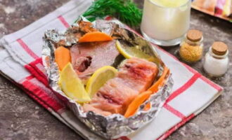 We form a neat boat from pieces of foil. Place fish pieces, carrot slices and lemon slices in it.