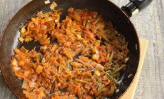 Después de 5 minutos, abre la tapa, agrega la pasta de tomate a la sartén y fríe las cebollas y los pepinos durante 3-4 minutos. Luego vierte inmediatamente el contenido de la sartén en la sartén con el caldo.