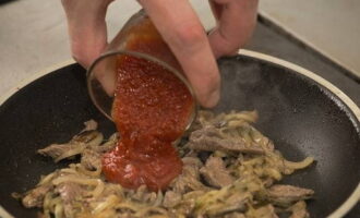 Voeg ingelegde komkommers toe aan de pan en voeg na 2-3 minuten tomatensaus toe. Breng het gerecht op smaak met peper en zout, zet het vuur lager en laat sudderen tot het vlees gaar is.