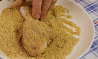 After the marinating procedure, actively roll each drumstick in breadcrumbs on all sides and transfer to parchment.