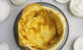 To assemble the cake, take a springform pan with a diameter of 20 centimeters. Place a pancake on the bottom. Next, we form the walls, laying out the pancakes so that they lie on the bottom and hang over the edges.