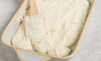 Grease a heat-resistant form with butter and fill it with curd dough. Level with a spatula.