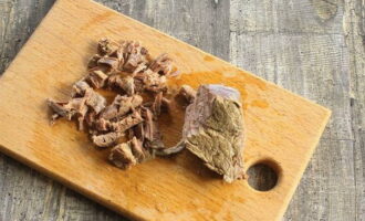 Retire a carne cozida do osso e corte em pedaços pequenos. Coloque a carne e as salsichas no caldo, mexa e cozinhe por 5 minutos.